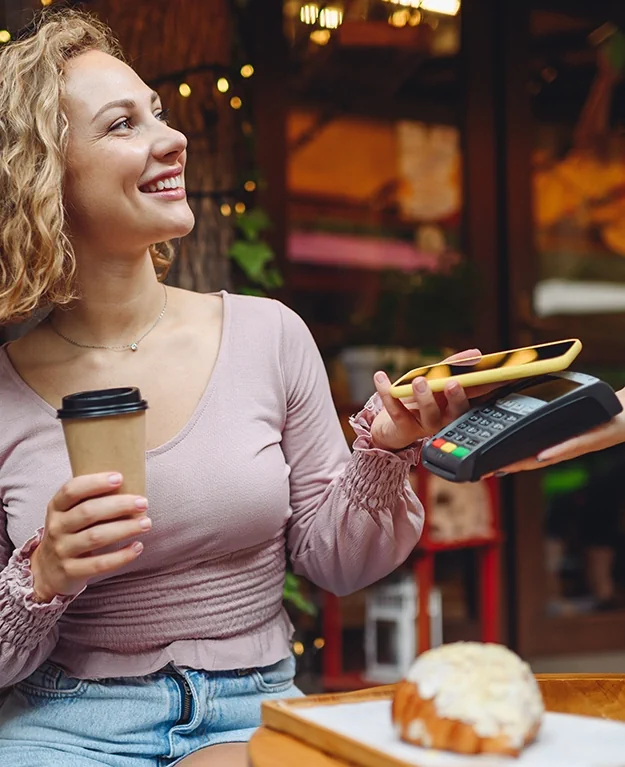 Frau bezahlt mit Bankkarte auf dem Smartphone im Cafe