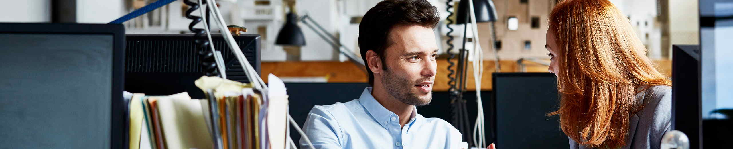 Ein Mann und eine Frau sitzen in einem Büro und reden miteinander