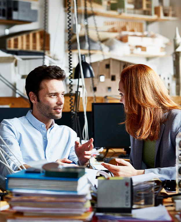Ein Mann und eine Frau sitzen in einem Büro und reden miteinander