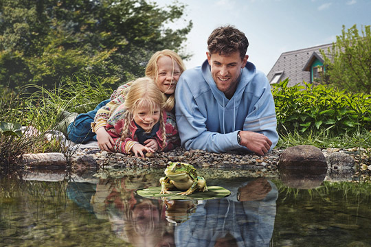 Dominic Thiem mit 2 Kindern liegend vor einem Teich