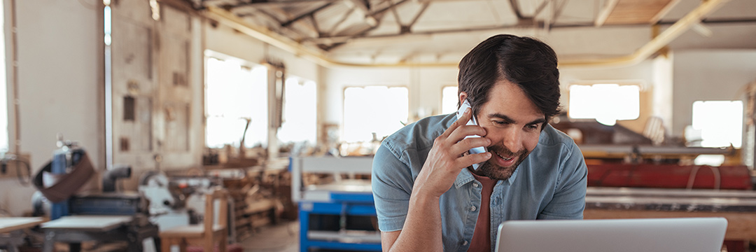 Man talking on the phone while sitting in front of his laptop