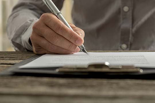 Großaufnahme einer Hand die etwas auf einen Zettel schreibt