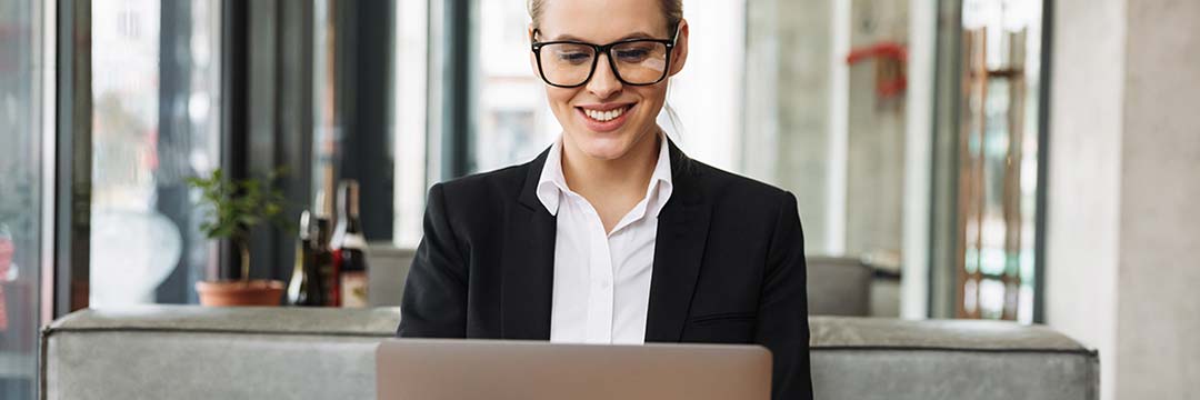 Eine Frau sitzt in einem Kaffeehaus und arbeitet auf ihrem Laptop