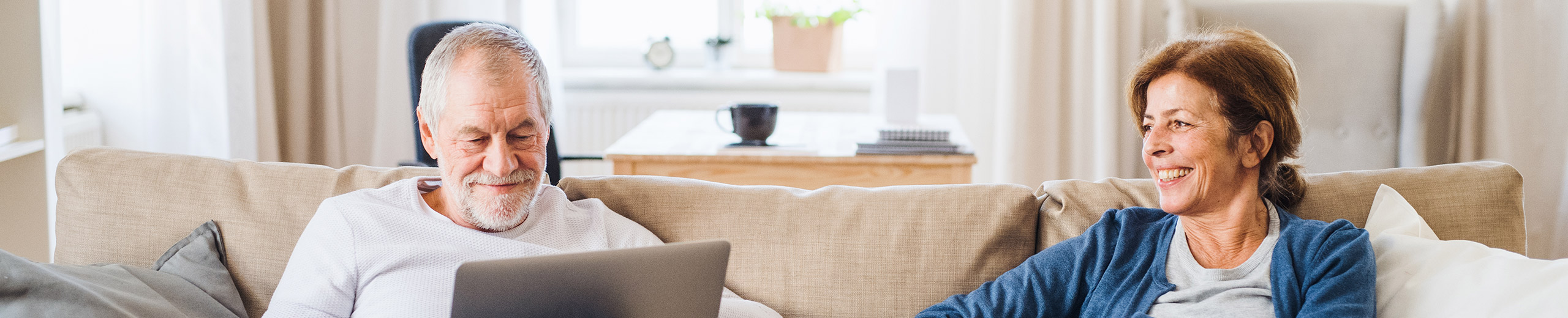 Eine ältere Frau und ein älterer Mann sitzen gemeinsam auf der Couch im Wohnzimmer