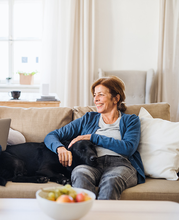 Eine ältere Frau und ein älterer Mann sitzen gemeinsam auf der Couch im Wohnzimmer