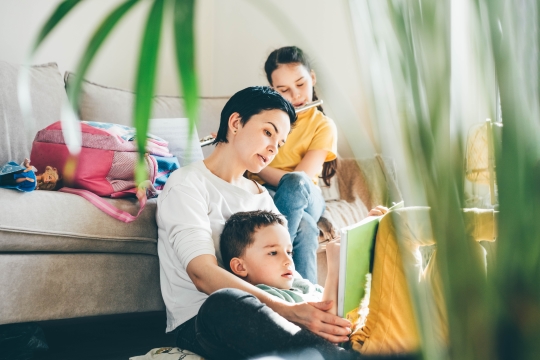 Eine Frau mit ihren beiden Kindern im Wohnzimmer