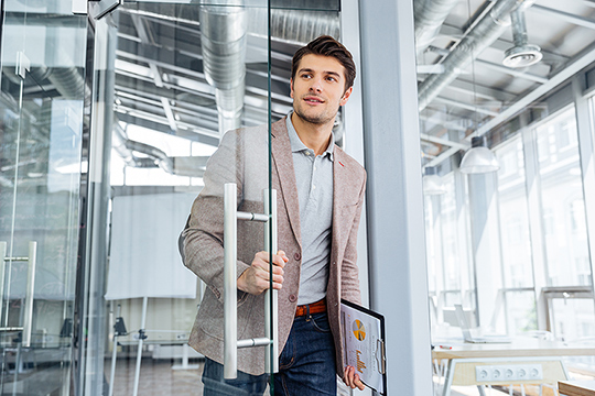 Ein Mann betritt durch eine Glastür ein Büro