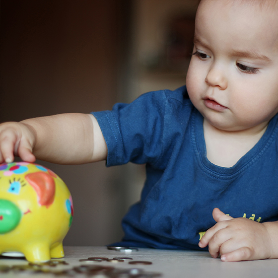 Kleines Kind steckt Geld in Sparschwein