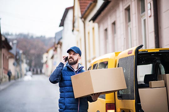 Mann mit Handy am Ohr und Paketen in der Hand